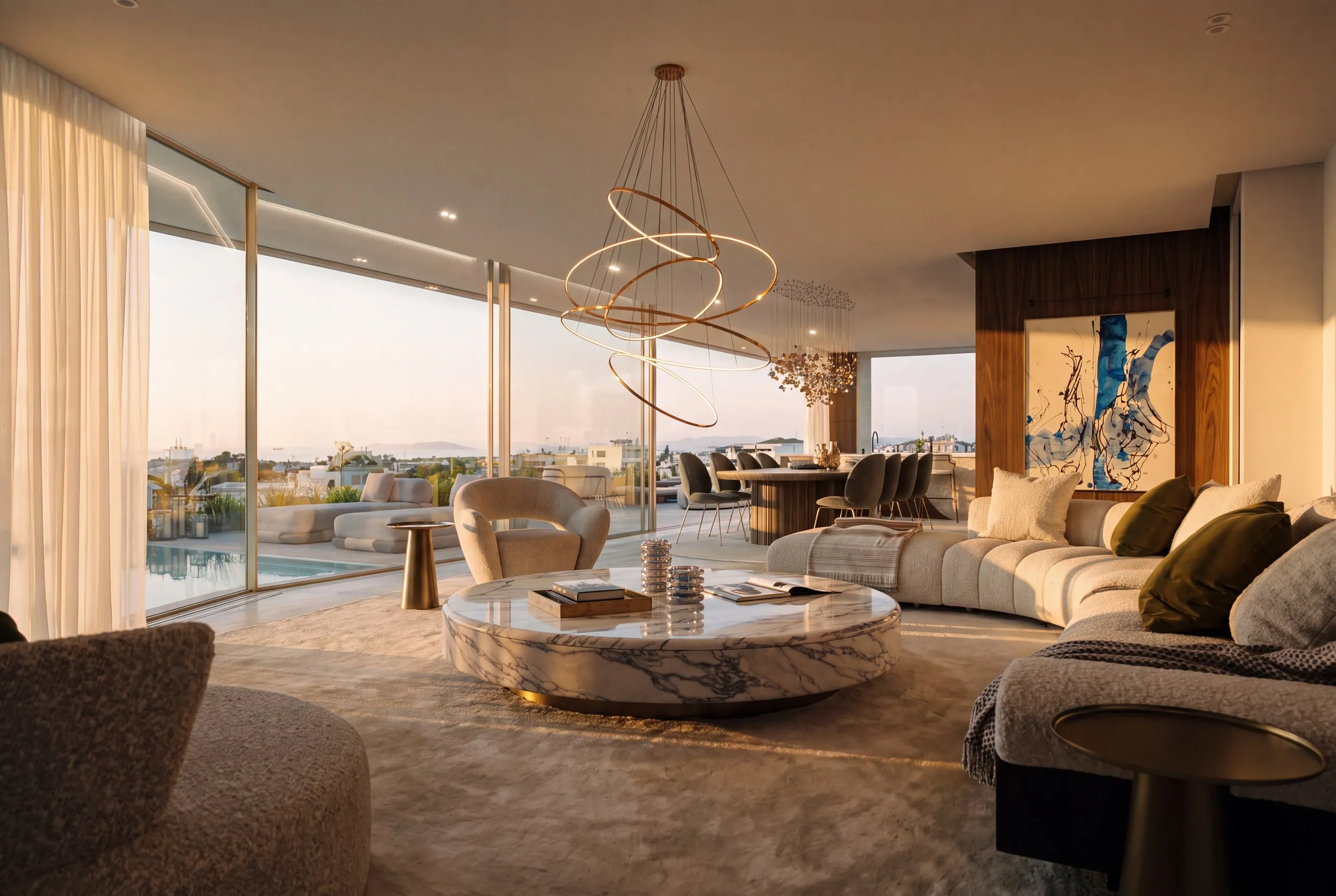 The Penthouse living room at sunset: curved sofas, a round marble table and the sculptural chandelier